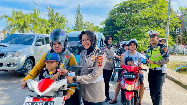 Personel Satlantas Polres Maros membagikan selebaran imbauan keselamatan serta coklat dan bunga bagi pengendara di Maros. (Sulselsatu/Indra Sadli Pratama)