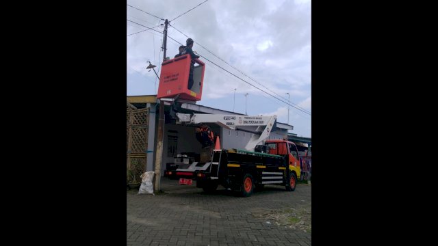 Personel UPT Lampu Jalan Dinas PU Makassar sedang memperbaiki lampu jalan. 