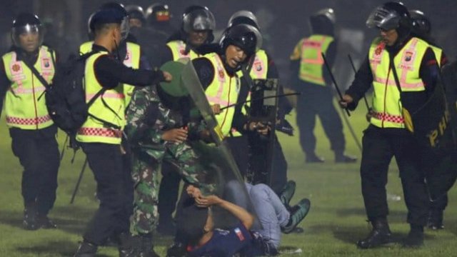 Aparat kepolisian saat memukuli suporter yang masuk di lapangan (dokumen: ist)