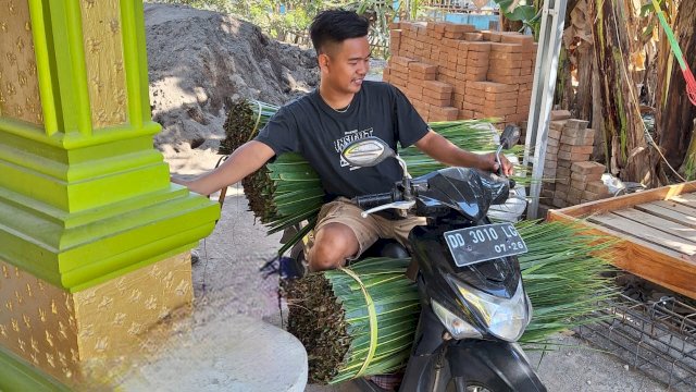 Daeng Sila saat mengantar daun kelapa kepada pekerja di salah sattu rumah warga. Foto: Sri Wahyu Diastuti/Sulselsatu.com