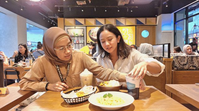 Dua pelanggan yang melihat menu dari The People's Cafe di MaRI Makassar. Foto: Sri Wahyu Diastuti / Sulselsatu.com