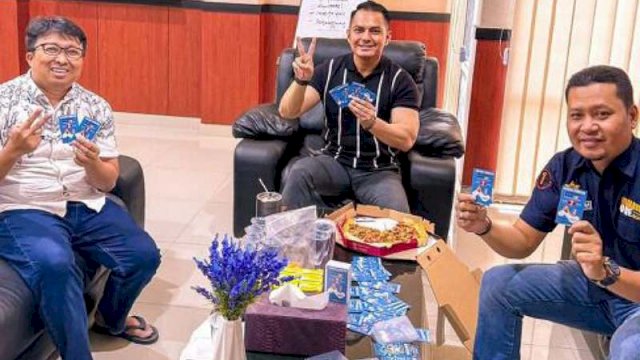 Kepala Samsat Makassar Yarham Yasmin (tengah) berpose salam 2 jari sembari menunjukkan kartu nama paslon Andi Sudirman Sulaiman-Fatmawati Rusdi. Ist